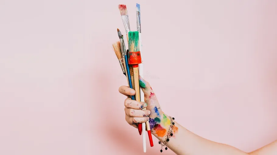 Bunte Pinsel von bemalter Hand gehalten.