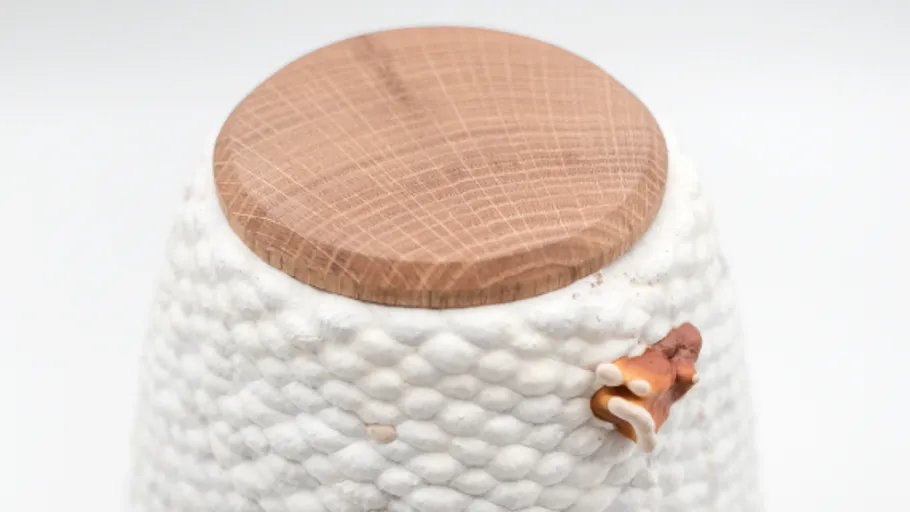 White textured pot with wooden lid.
