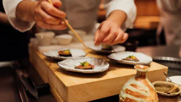 Chef preparing sushi plates in a kitchen.