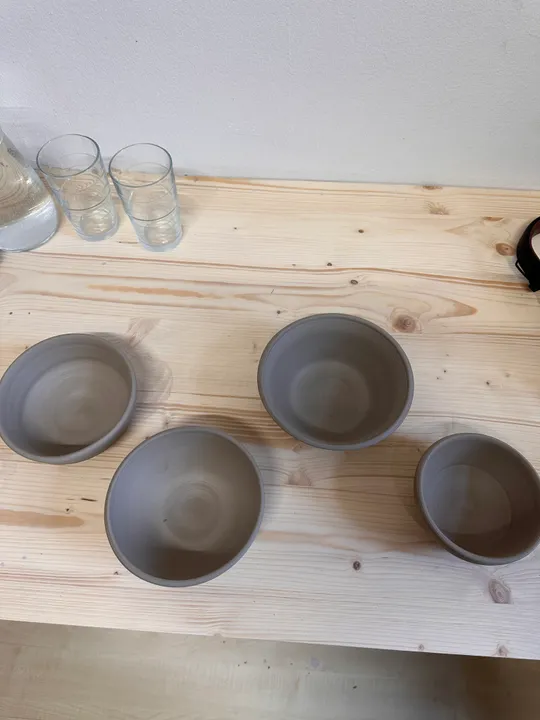 Vier Ton-Schalen auf einem Holztisch.