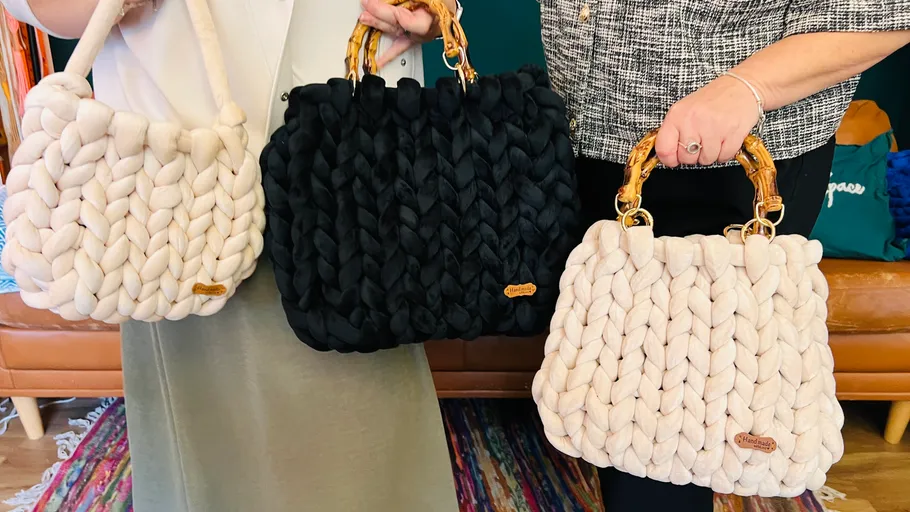 Three woven handbags held by two people indoors.
