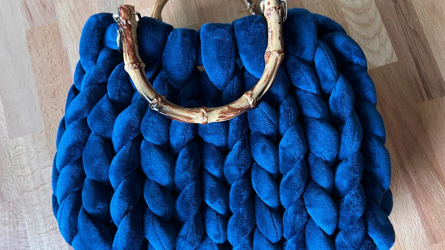 Blue knitted handbag with wooden handles.