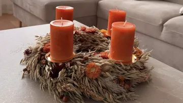 Orange candles on a decorative wreath indoors.