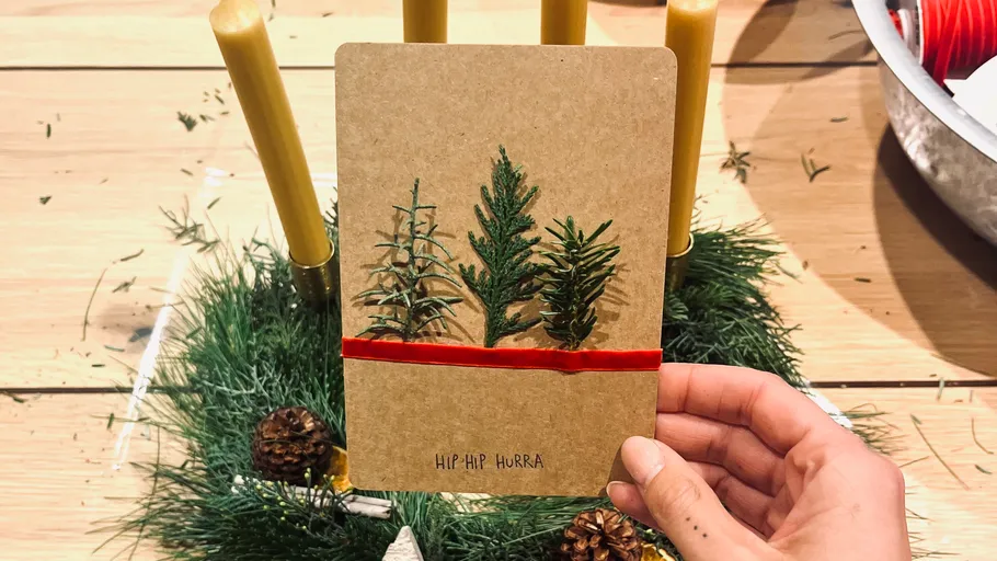 Hand holding card with tree design, festive setting.