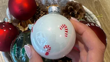 Hand holding decorated Christmas ornament indoors.