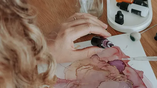 Hand applying ink to paper with pipette.