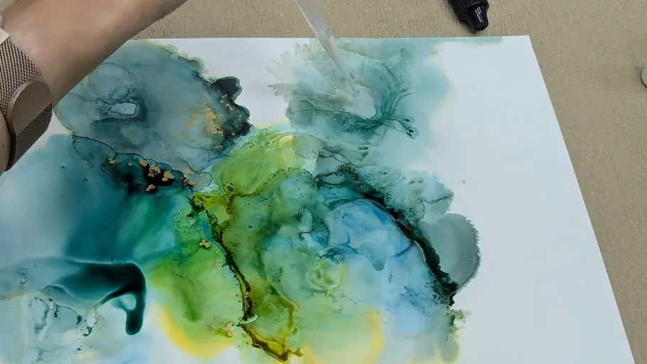 Person drips alcohol ink on canvas.