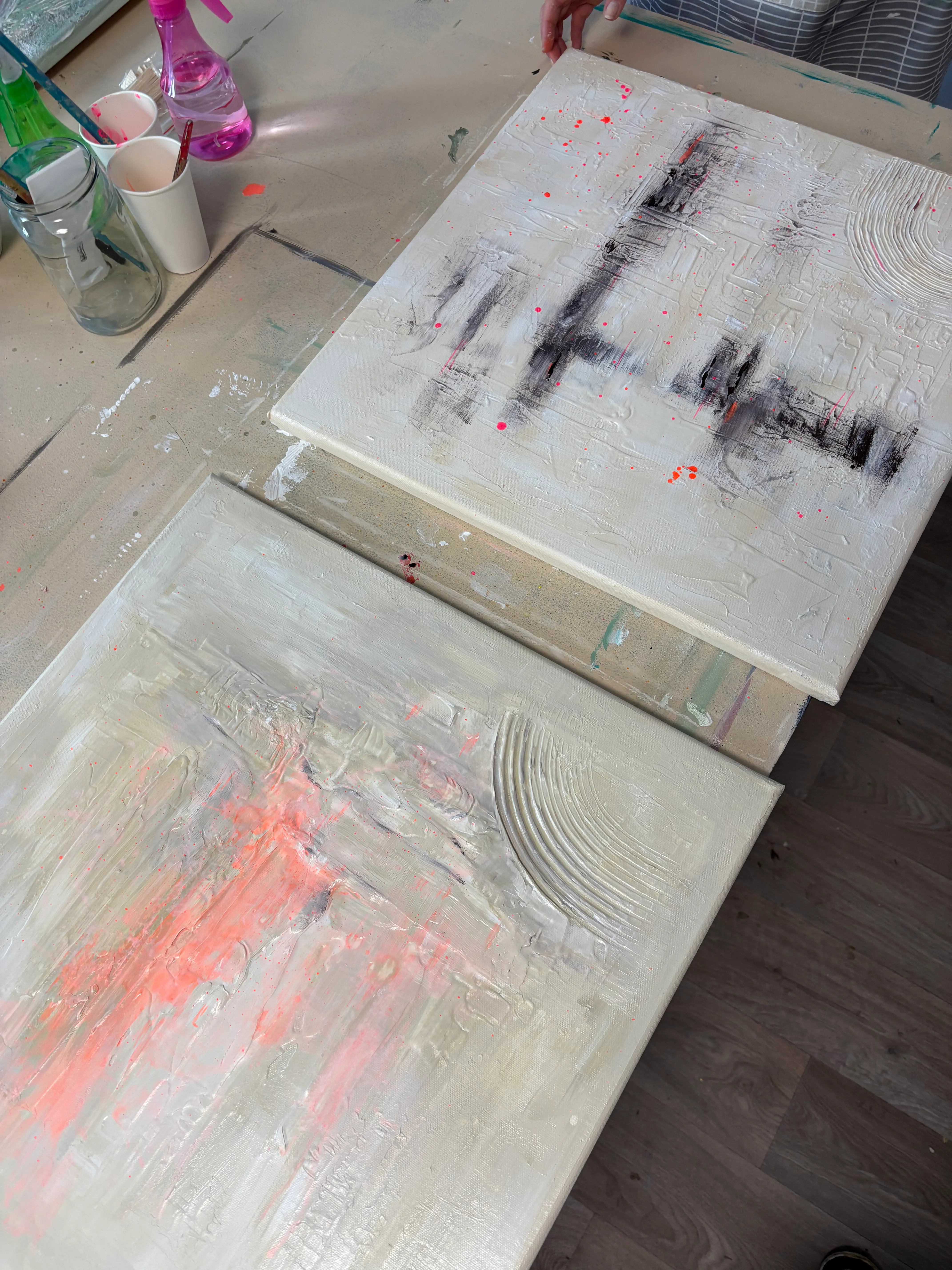 Zwei abstrakte Gemälde auf einem Tisch.