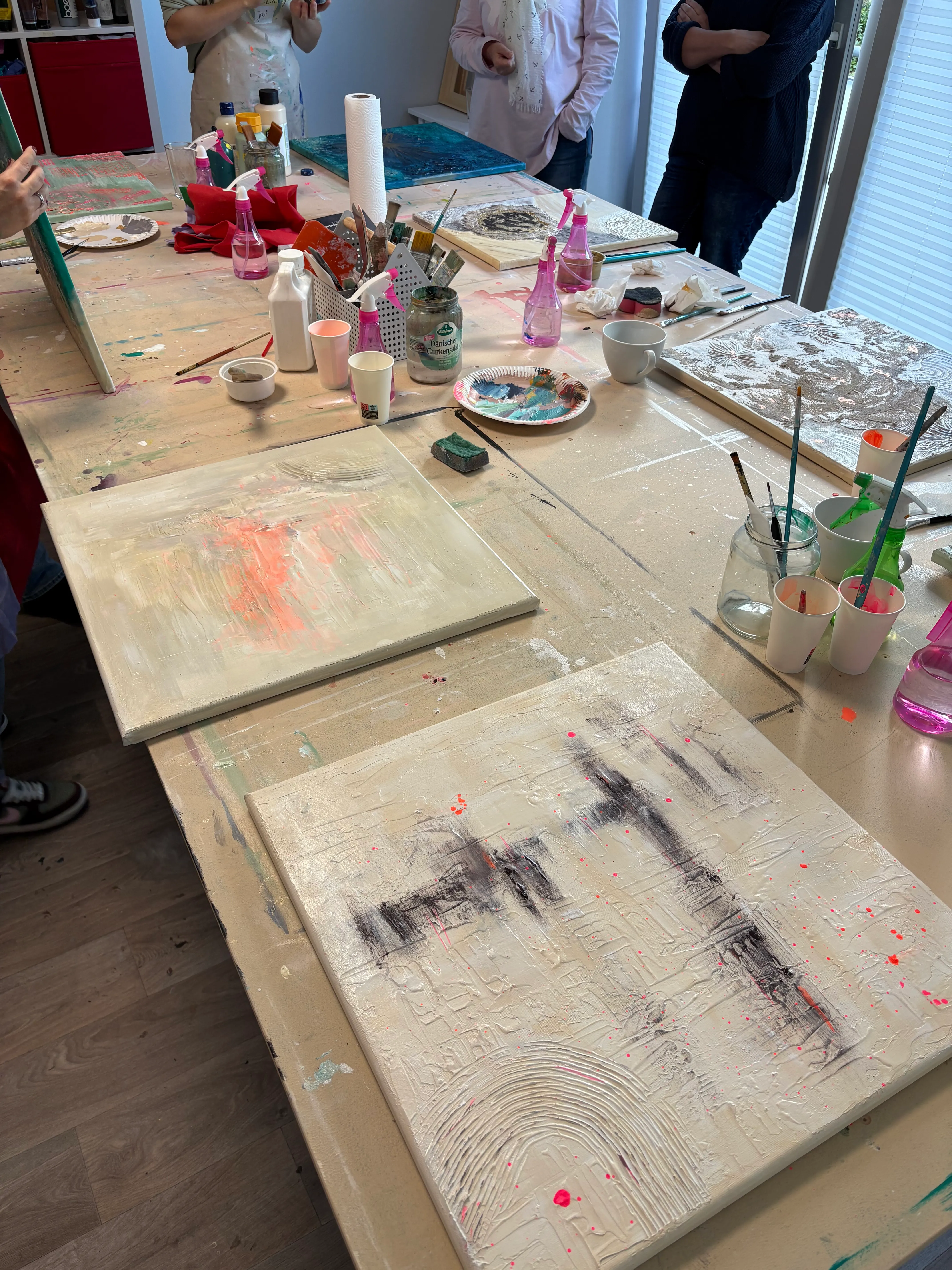 People painting canvases in art studio.