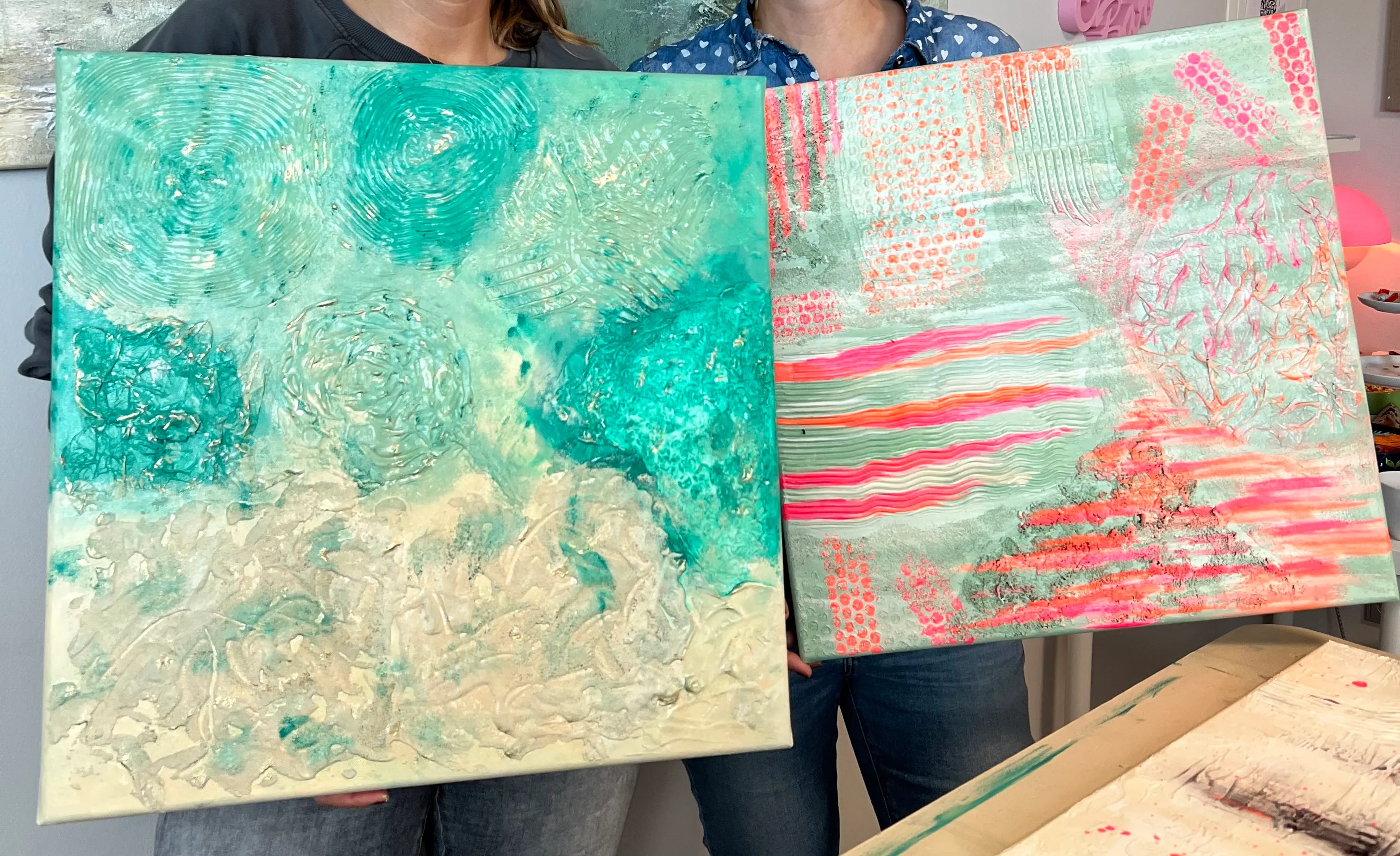 Two paintings held by people indoors.