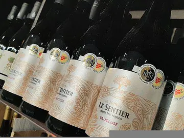 Wine bottles are on a shelf with labels and awards.