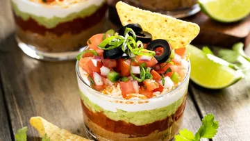 Layered dip with tortilla chips and lime.