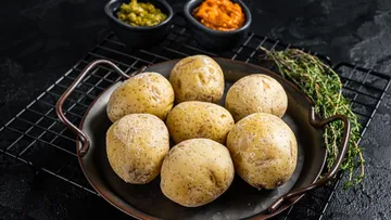 Boiled potatoes in a pan with sauces nearby.