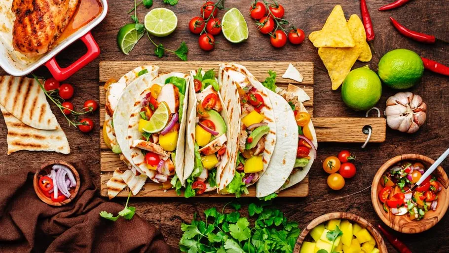 Tacos with vegetables on wooden board.