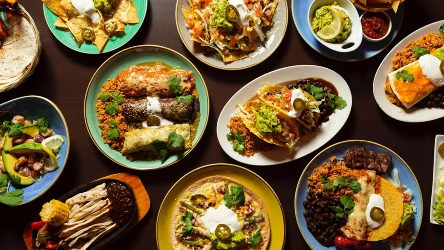 Plates of Mexican food on a dark table.