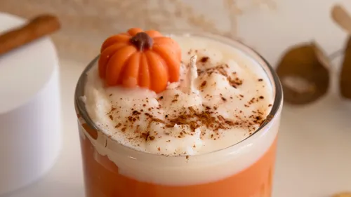 Pumpkin-shaped decoration on whipped cream drink.