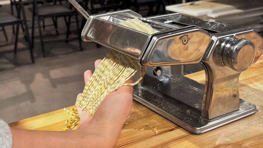 Person macht Nudeln mit einer Nudelmaschine.