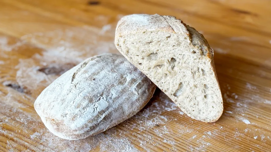 Two loaves of bread on a wooden surface.