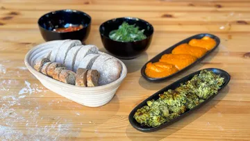 Brot und Dips auf einem Holztisch.