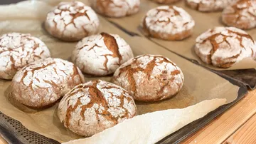 Crusty bread rolls on baking tray.