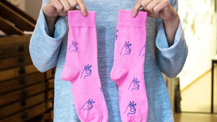 Person hält pinke Socken mit Handabdruck.