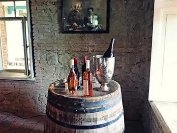 Wine barrel with bottles and cooling container in rustic space.
