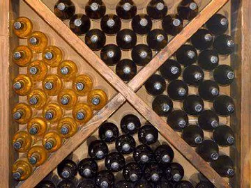 A bottle of wine is stored on a wooden rack.