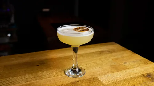 Cocktail glass with dried lime on wooden table.