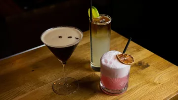 Three cocktails on wooden bar table.
