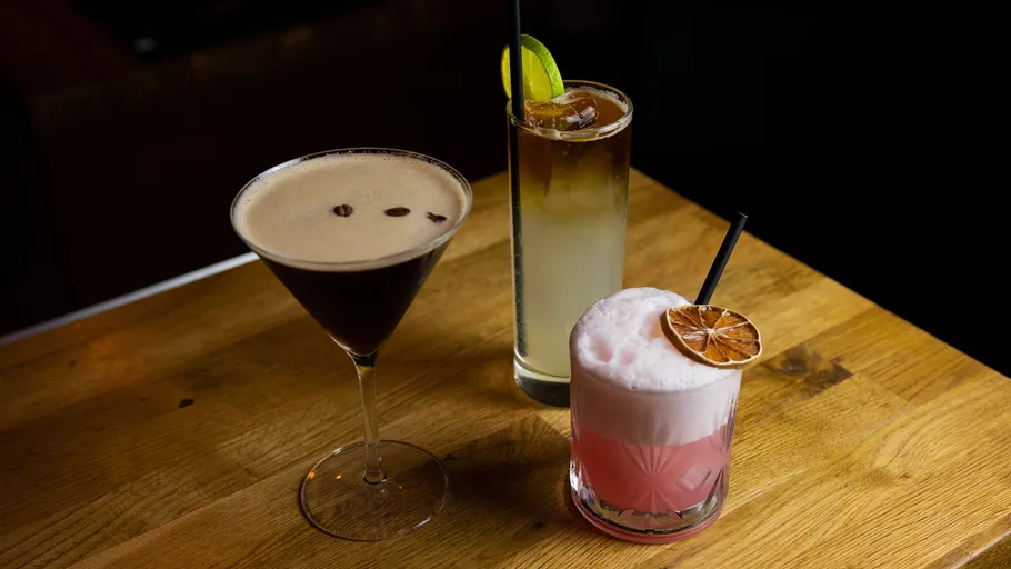 Three cocktails on wooden bar table.