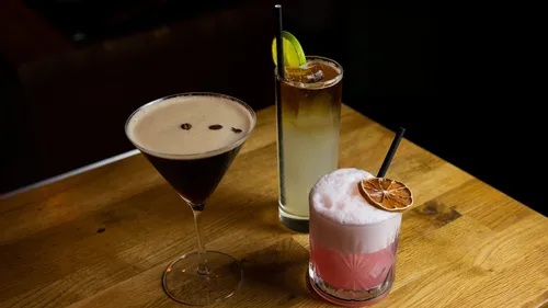 Drei Cocktails auf einem Holztisch.