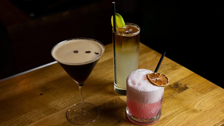 Drei Cocktails auf einem Holztisch.