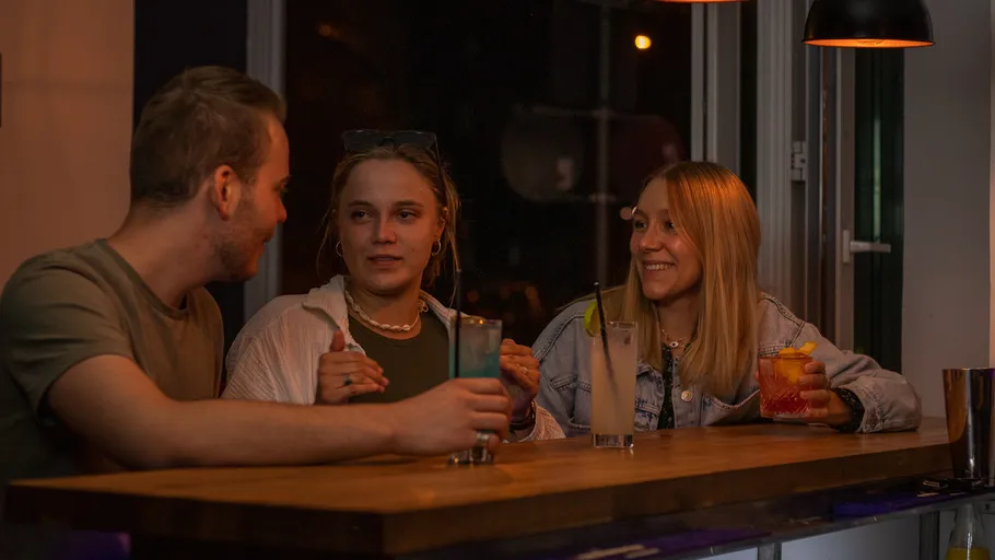 Drei Personen unterhalten sich an einer Bar.