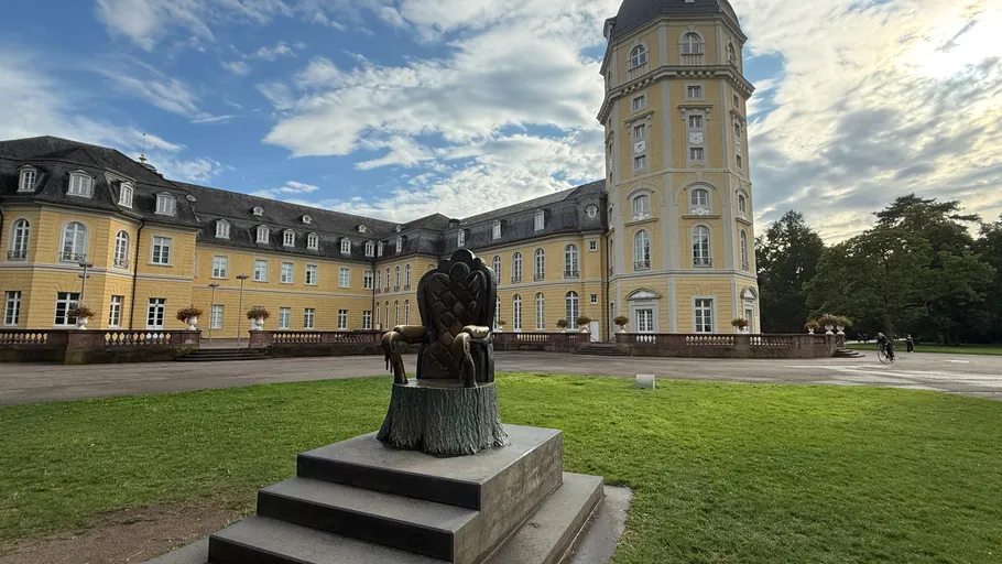 Statue in front of historic yellow castle building.