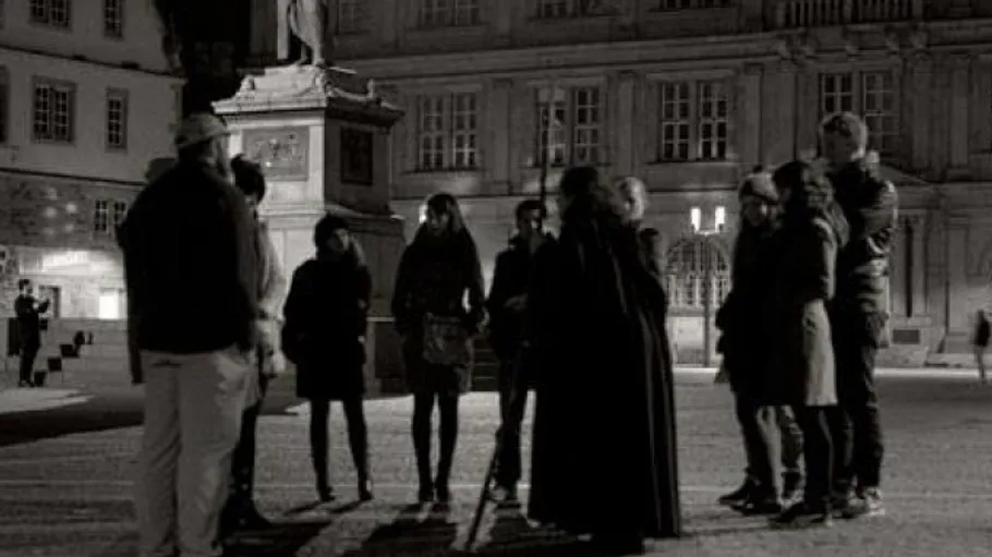 Gruppe von Menschen steht auf nächtlichem Platz.