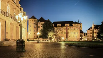 Historic building lit at night, streetlamps glowing.