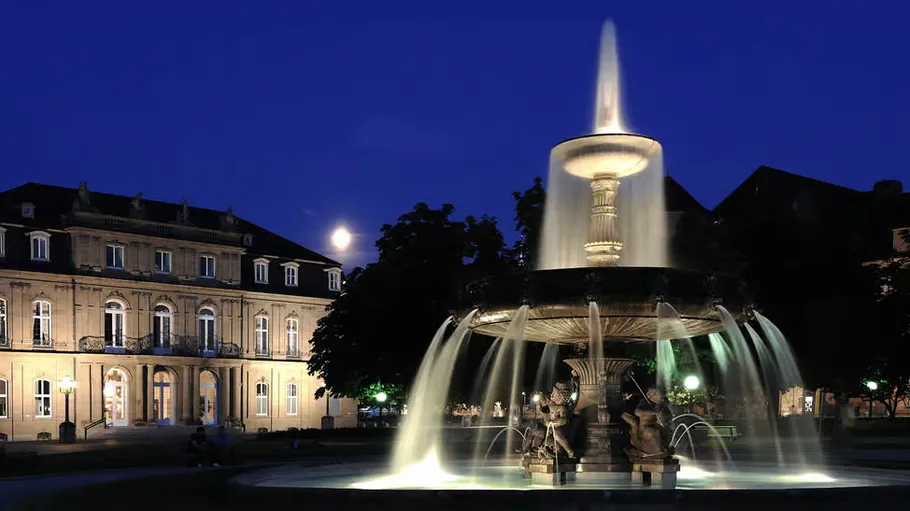 Fountain illuminated at night in city square.
