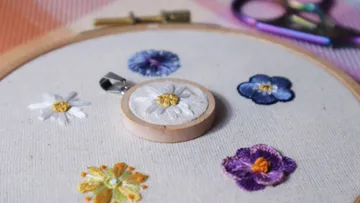 Gestickte Blumen und Anhänger auf Stoff.