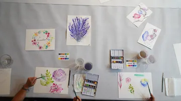Two people painting with watercolors on a table.