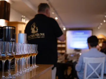 Gläser mit Getränken stehen auf dem Tisch, Präsentation im Hintergrund.