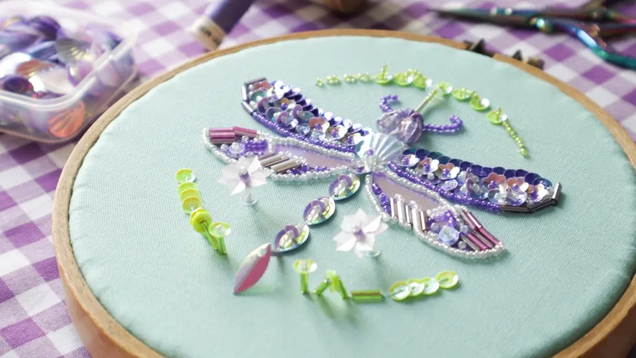 Beaded dragonfly design on fabric hoop.