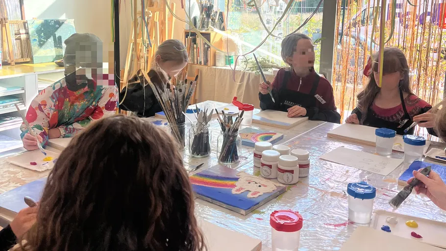 Kinder malen an einem Tisch im Kunststudio.