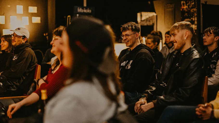 Menschen sitzen in einer gemütlichen Innenveranstaltung.