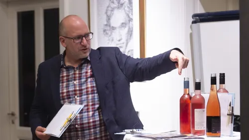 Man pointing at wine bottles on a table.