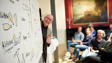 Man presenting diagrams to seated audience.