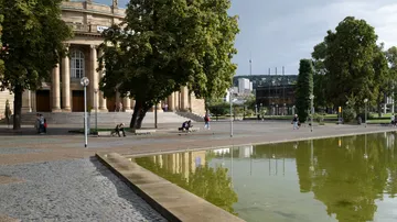 People sitting near a building and pond.