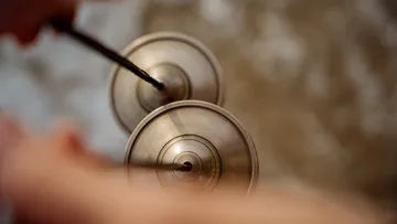 Close-up of person playing Tibetan cymbals.
