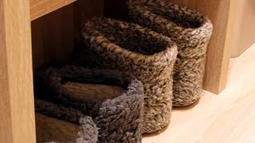 Furry slippers under a wooden shelf.