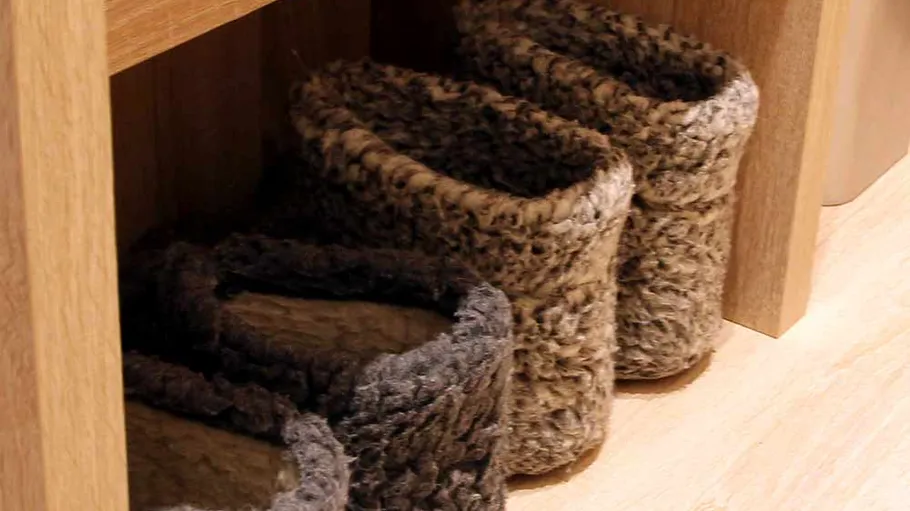 Fellige Hausschuhe unter einem Holzregal.