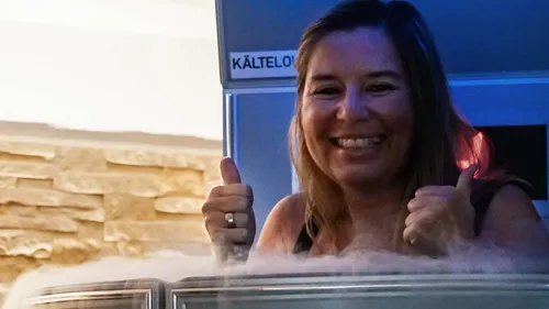 Lächelnde Frau zeigt Daumen hoch in Kältekammer.